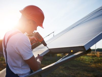 using-cordless-screwdriver-male-worker-blue-uniform-outdoors-with-solar-batteries-sunny-day-2